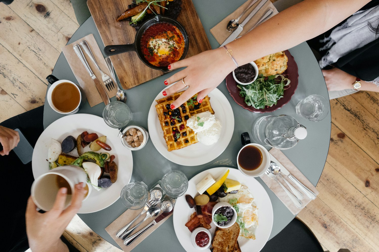 Een gedeelde brunchtafel met shakshuka, wentelteefjes, salades en koffie — grotendeels plantaardig